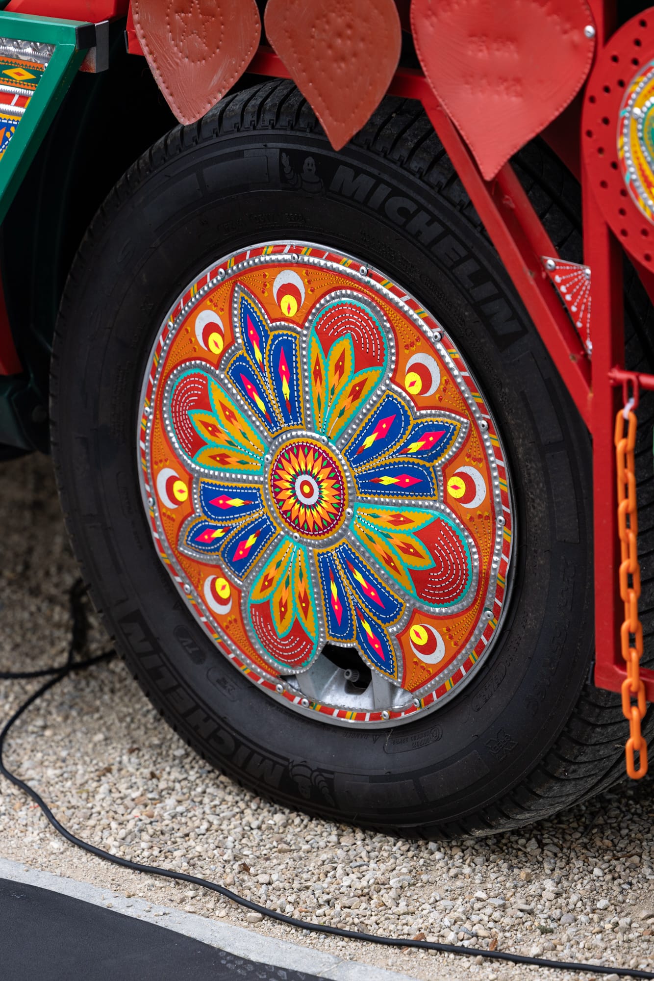a detail of a painted wheel hub cap on a colorful van that has been transformed into an artwork