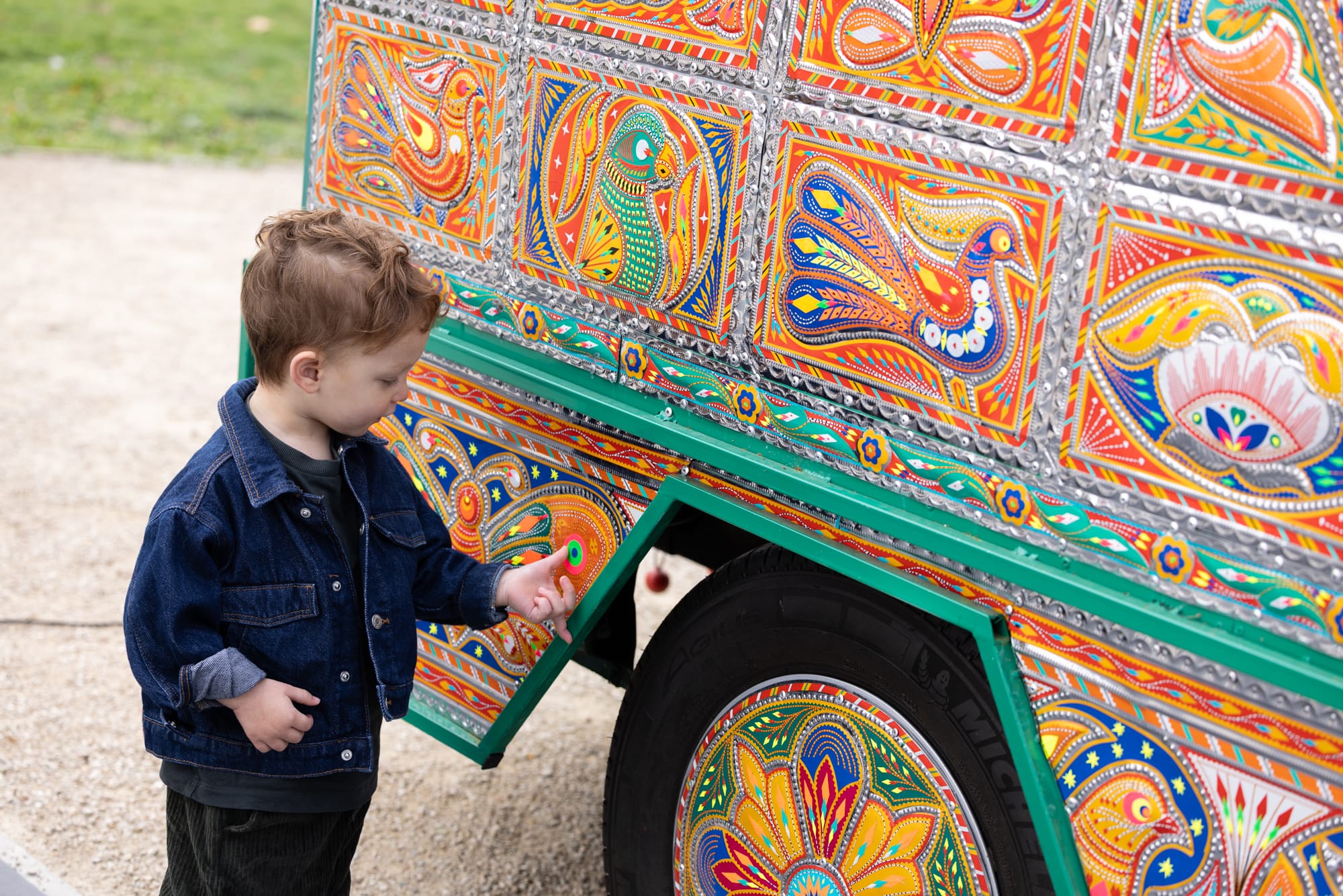 a young boy touches a decorative panel on a colorful van that has been transformed into an artwork