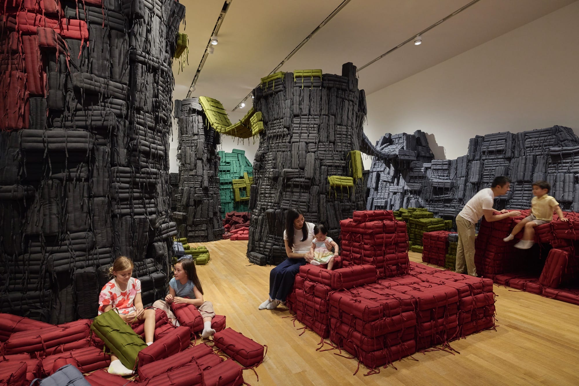 children and adults sit in a cushion filled room