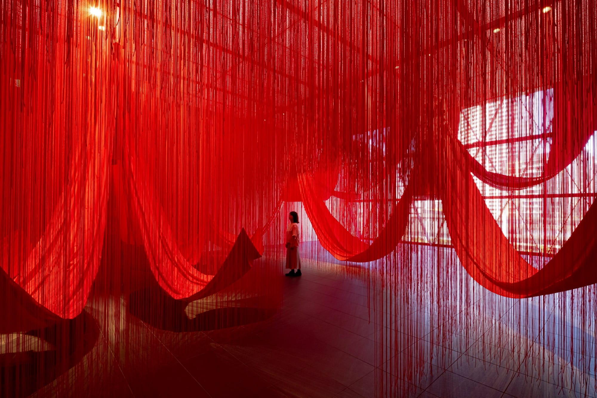 a person stands amid dangling red string