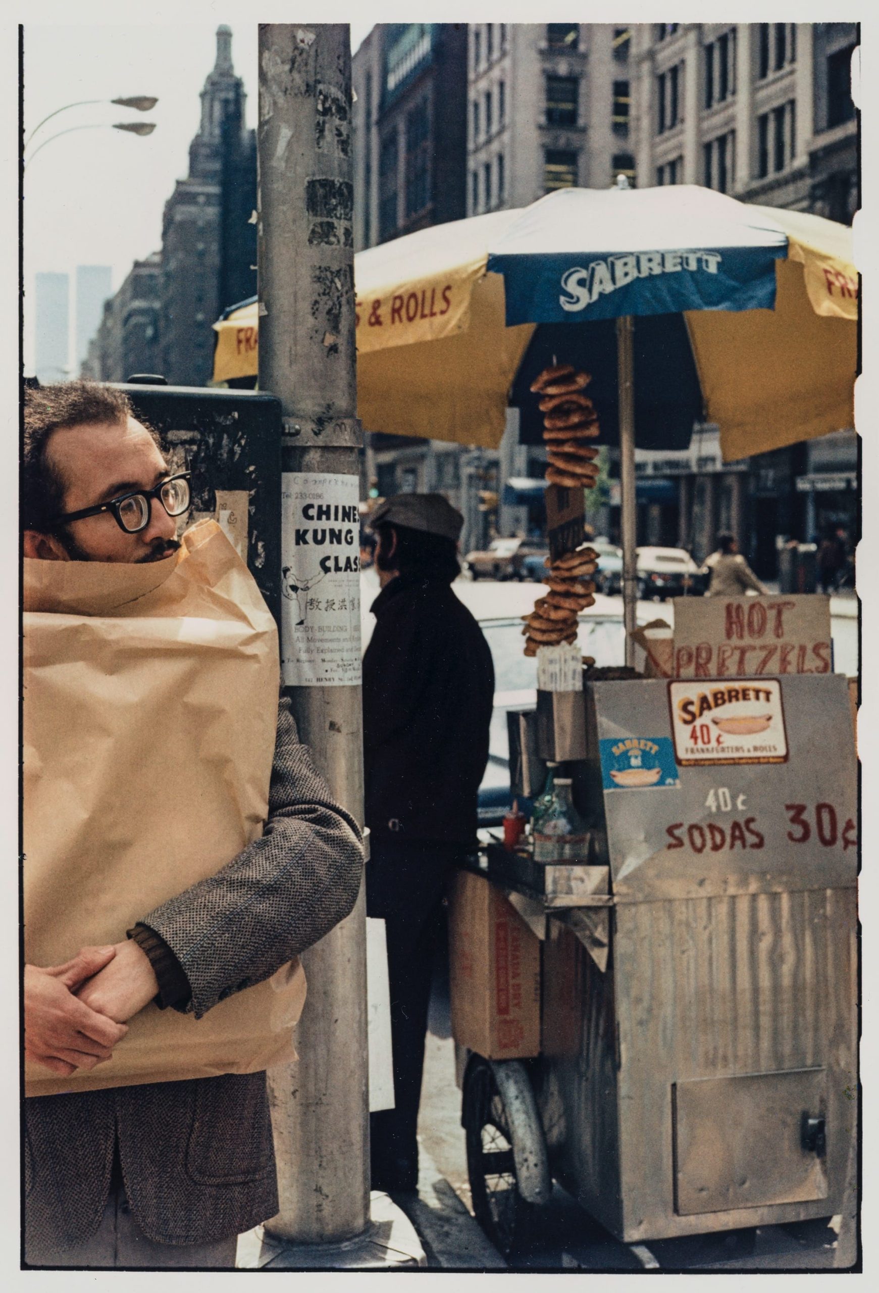 a photo by Helen Levitt of a man carrying a paper package and a hot dog and pretzel vendor in New York City