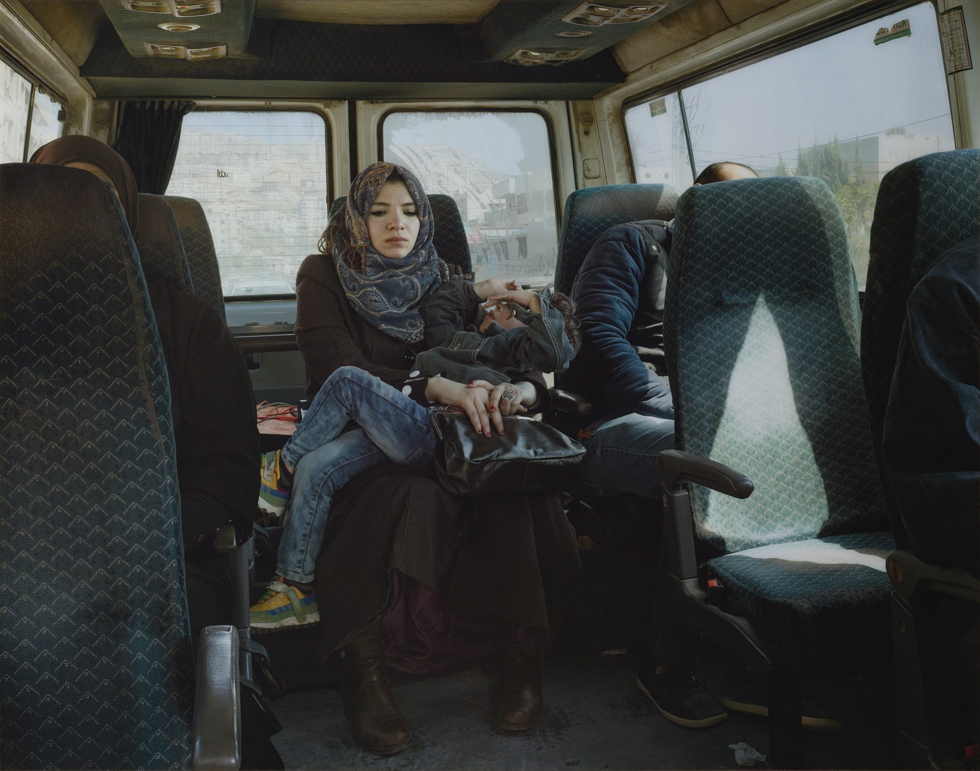 a photo by Luc Delahaye of a mother with her young boy on her lap, sitting in the back of a taxi