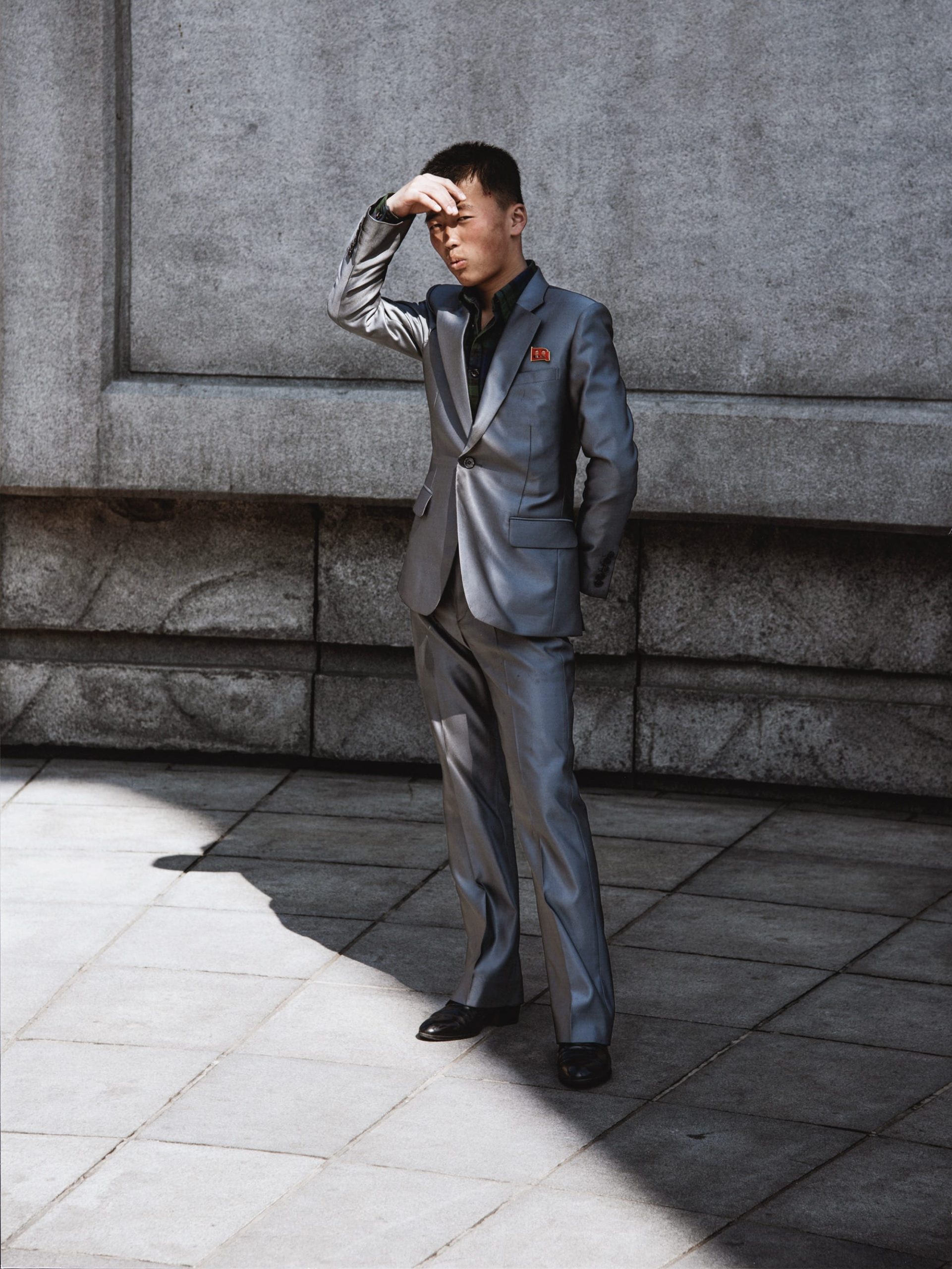 a photo by Matthew Connors of a man in a gray suit in Pyongyang