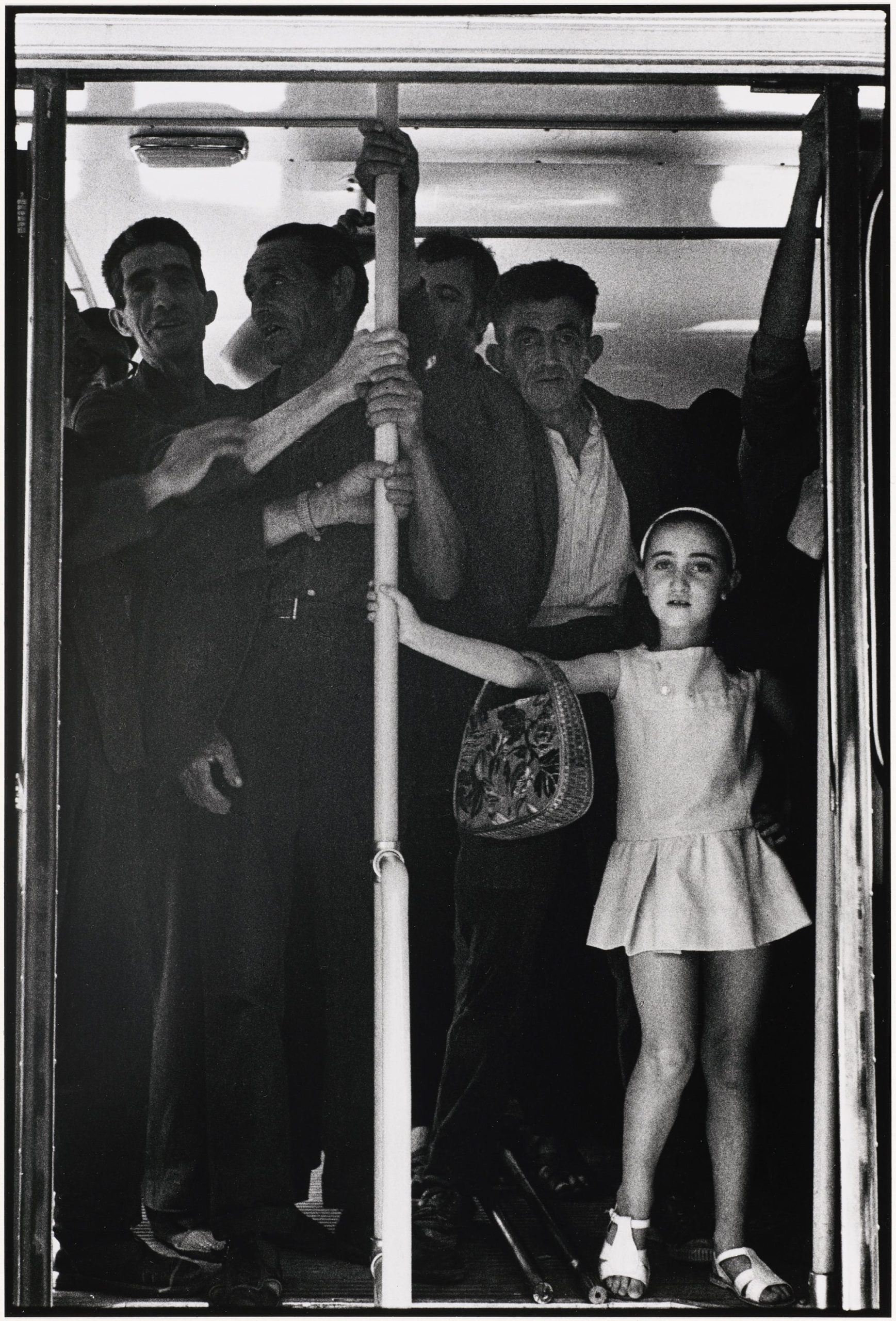 a black-and-white photograph by Cristobal Hara of a child and other adults standing on a bus or train