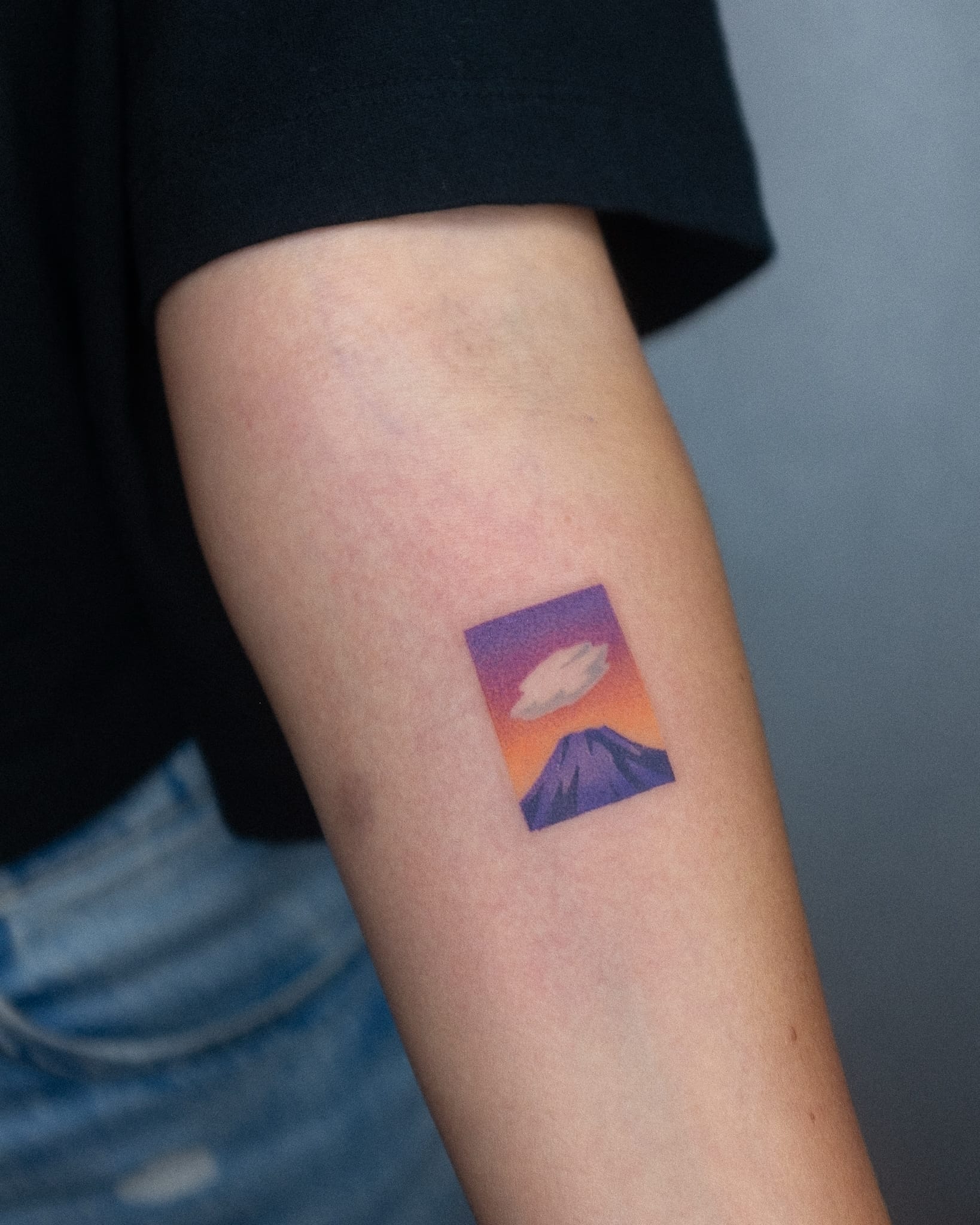 a white arm with a tattoo by Nano Ponto of a vibrant landscape gradient