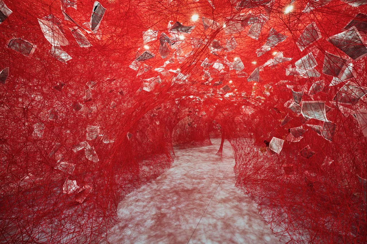 a full-room installation of red fiber and paper pages by Chiharu Shiota