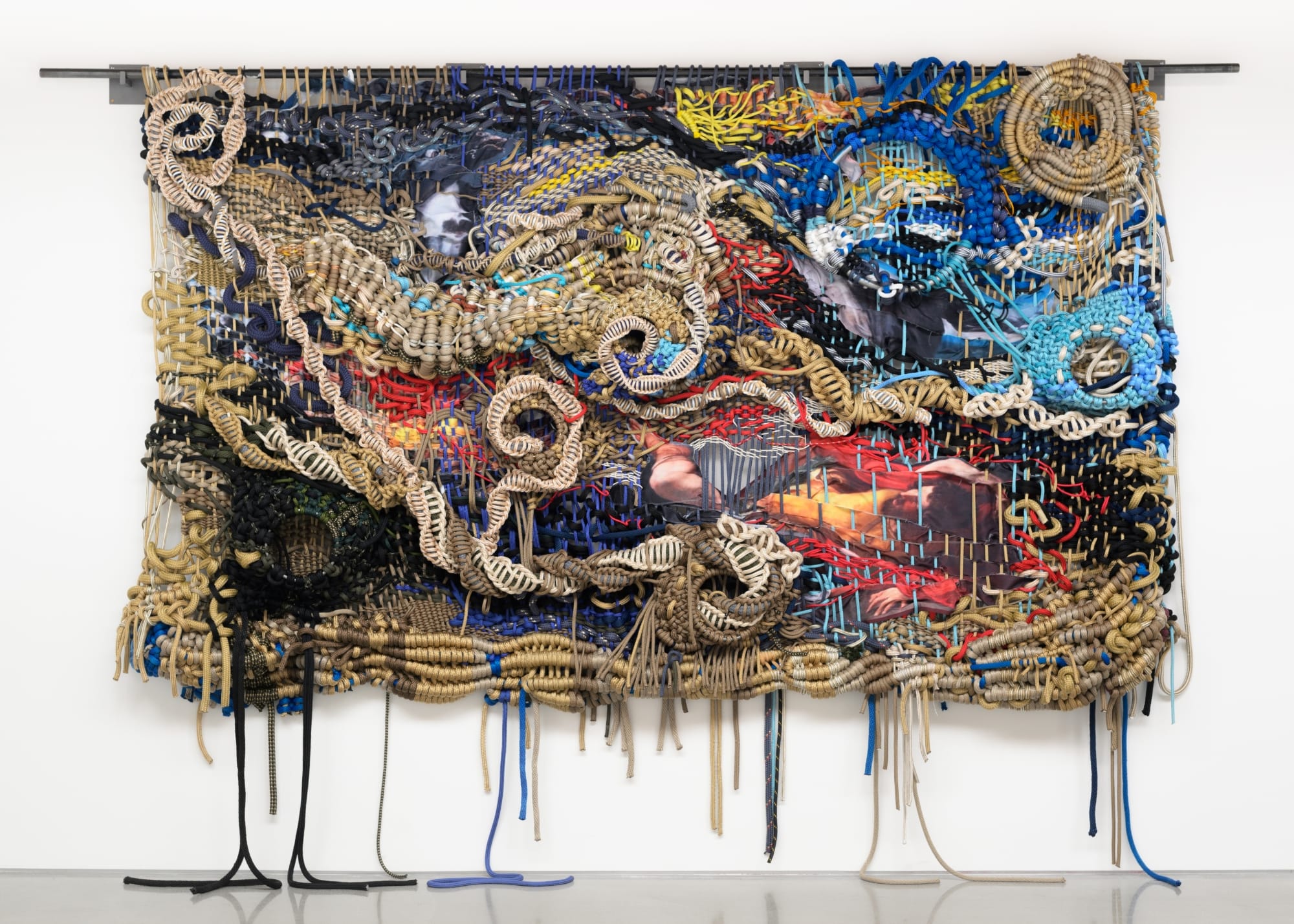 a colorfully knotted rope work by Jacqueline Surdell hanging from a bar