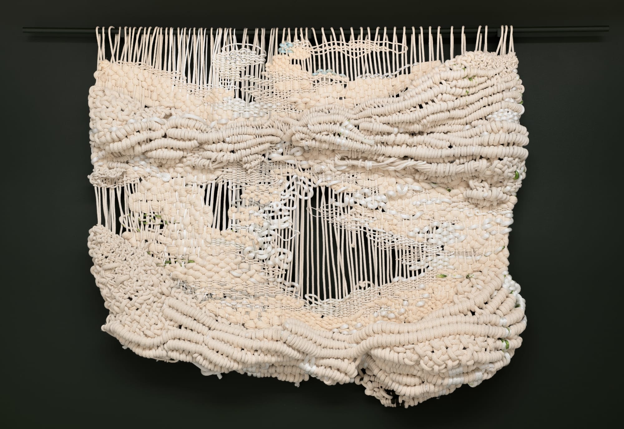a knotted white rope work by Jacqueline Surdell hanging from a bar